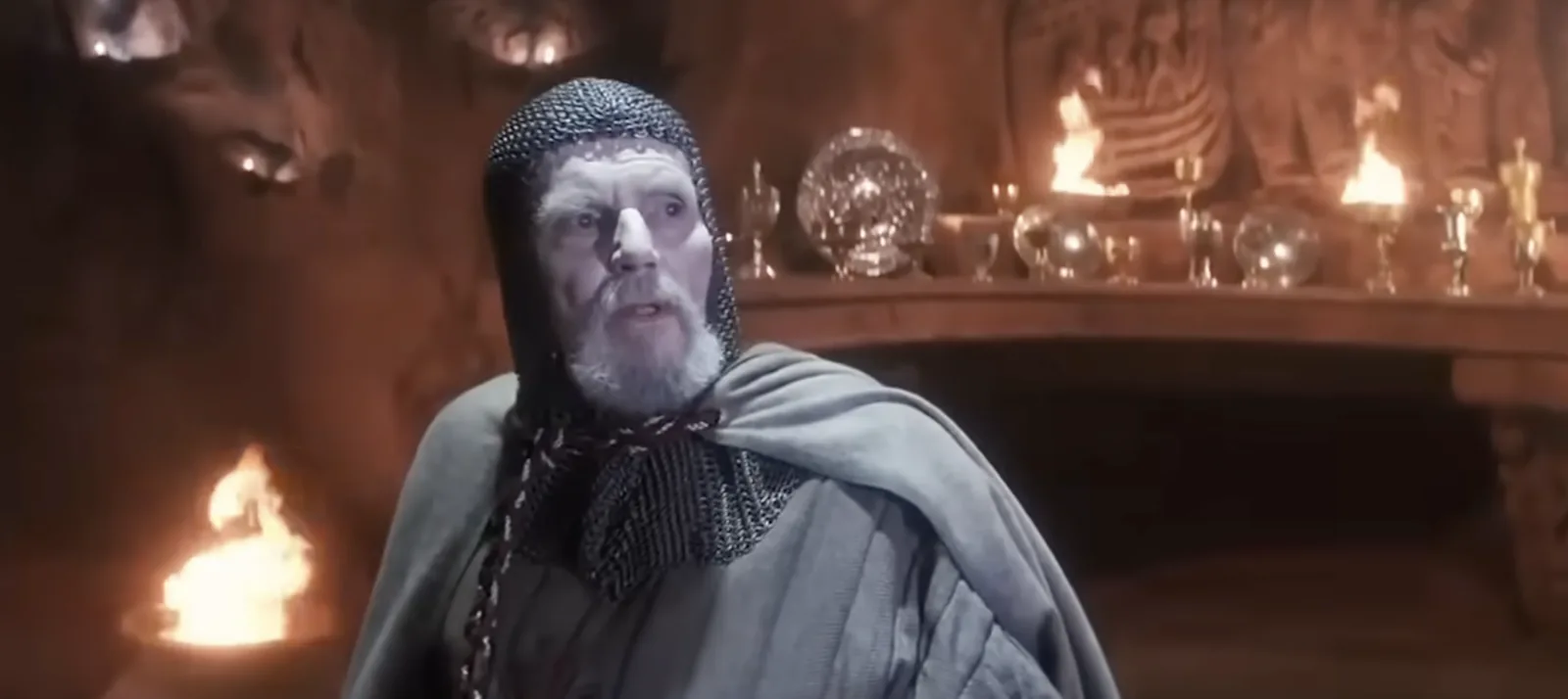The Grail Knight from Indiana Jones and the Last Crusade, standing before a table of chalices in the torchlit temple, mid-sentence.